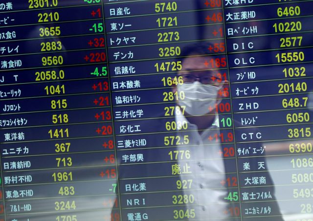 A man wearing a protective face mask is reflected on a stock quotation board at a brokerage, amid the coronavirus disease (COVID-19) outbreak, in Tokyo